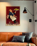 Lemon Delivery art print in a natural oak frame above a cognac leather sofa beside a black wall lamp