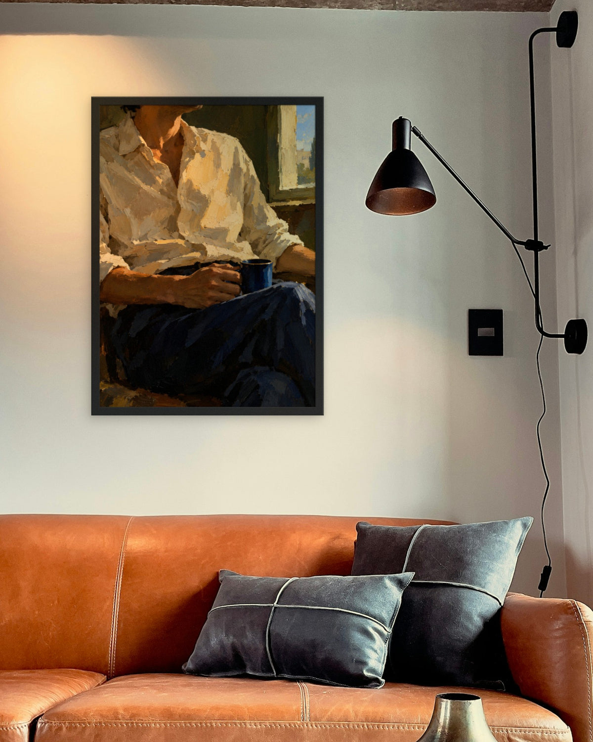 Slow Morning art print in a black frame above a cognac leather sofa beside a black wall lamp