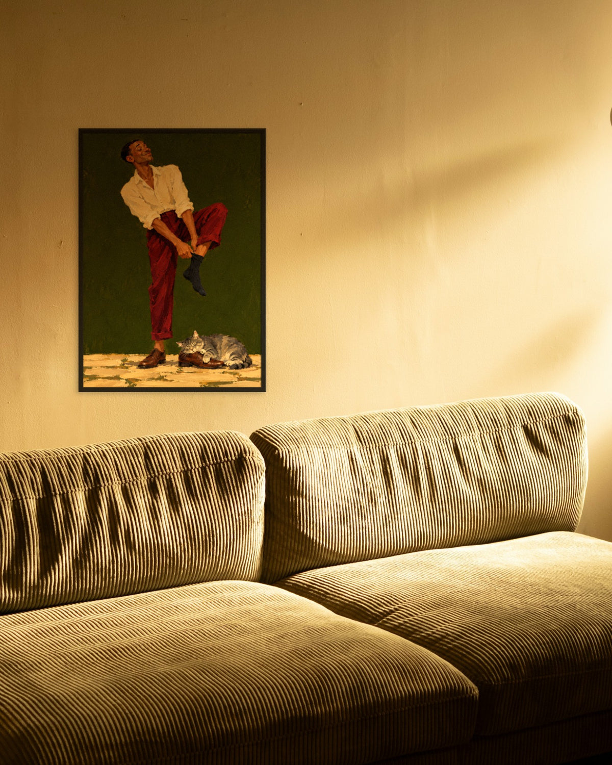 Sunday Socks art print in a black frame above an olive corduroy sofa in warm evening light